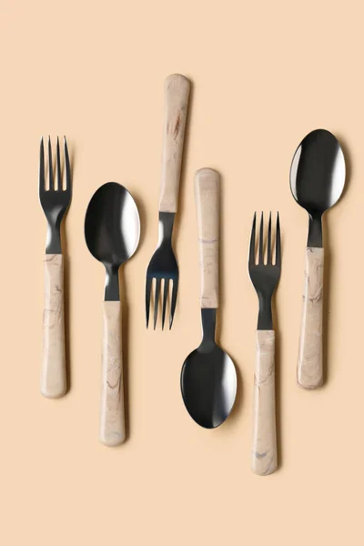 带米色背景塑料柄的不锈钢叉和勺子 — 图库照片