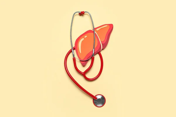 オレンジの背景に聴診器を備えた赤い紙の肝臓 — ストック写真