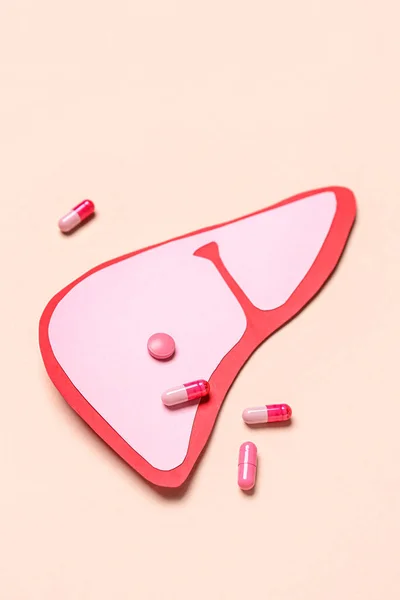 stock image Pink paper liver with pills on beige background
