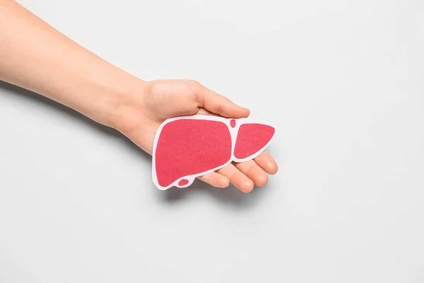 stock image Female hand holding red paper liver on grey background