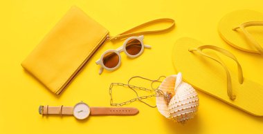 Sarı arka planda deniz kabuğu ve farklı aksesuarlar olan şık bir çanta.