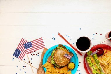 Lezzetli yemekler, içecekler ve hafif ahşap arka planda Amerikan bayrakları olan kompozisyon. Anma Günü kutlaması