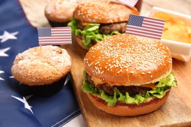 Lezzetli hamburgerleri, muffinleri ve Amerikan bayrağıyla ahşap pano, yakın plan. Anma Günü kutlaması