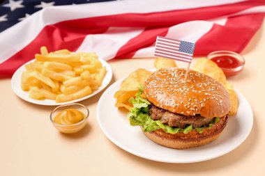 Lezzetli hamburgerli tabaklar, patates kızartması, patates cipsi, soslar ve renkli Amerikan bayrağı. Anma Günü kutlaması