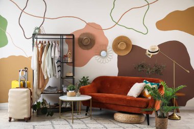 Kanepesi, raf ünitesi ve kıyafetleri olan şık bir oda.