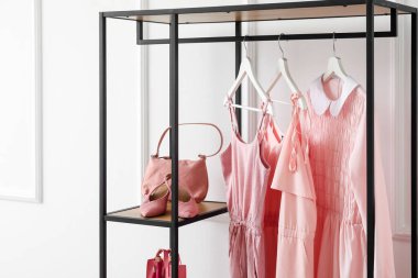 Elbiseli, çantalı ve ışıklı duvarın yanındaki ayakkabılı raf.