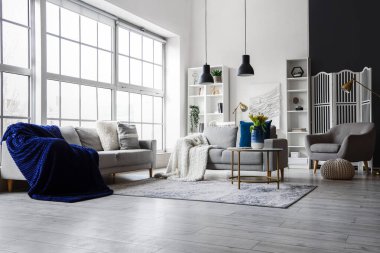 Büyük pencerenin yanında rahat kanepeleri ve kahve masası olan parlak bir oturma odası.