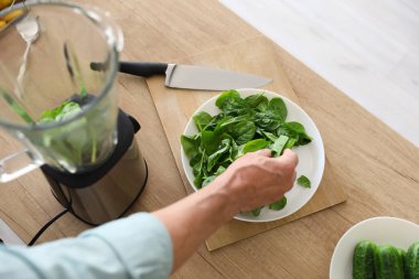 Olgun adam mutfakta ıspanaklı smoothie yapıyor, yakın plan.