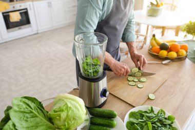Mutfakta salatalık kesen olgun bir adam, yakın plan.