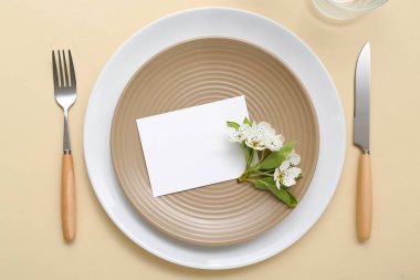 Boş davetiye kartı ve bej arka planda çiçek açan ağaç dalı olan güzel masa ayarları
