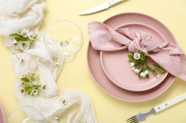 Sarı arka planda çiçek açan ağaç dalları olan güzel bir masa.