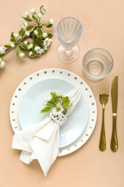 Çiçek açan ağaç dalları ve bej arka planda katlanmış peçeteyle güzel bir masa.