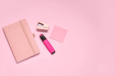 Pembe arka planda farklı kırtasiye malzemesi içeren yapışkan bir not.