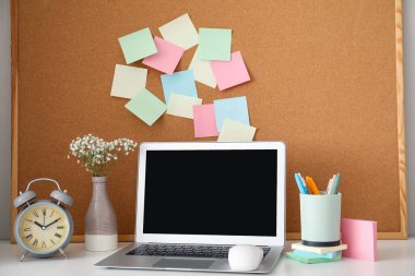 Masada yapışkan notlar ve dizüstü bilgisayarlı bir tahta var.