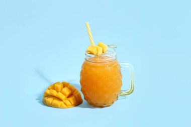 Mason kavanozu mavi arka planda taze mango smoothie.