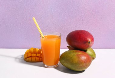 Mor arka planda bir bardak taze mango kokteyli.