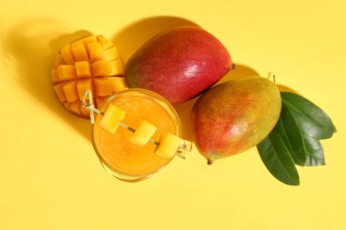 Turuncu arka planda bir bardak taze mango içeceği.
