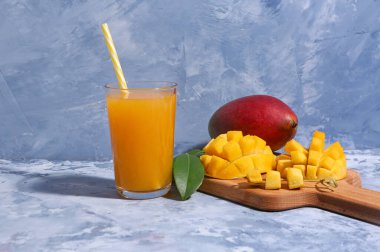 Mavi arka planda bir bardak taze mango püresi.