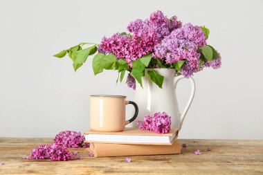 Sürahi güzel leylak çiçekleri, kahve ve kitaplarla beyaz duvarın yanındaki ahşap masada.