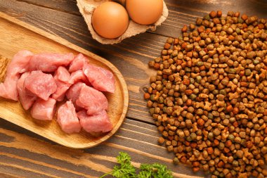 Kuru hayvan maması, çiğ et ve ahşap zeminde doğal ürünler.