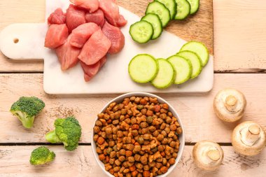 Kuru hayvan mamasıyla kompozisyon, çiğ et ve hafif ahşap arka planda doğal ürünler.