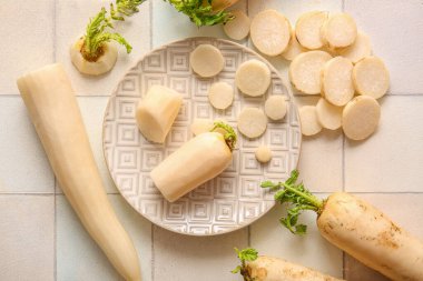 Beyaz fayans zemininde taze daikon turpları.