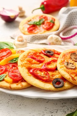 Farklı lezzetli mini pizzalarla kaplanmış, yakın plan.