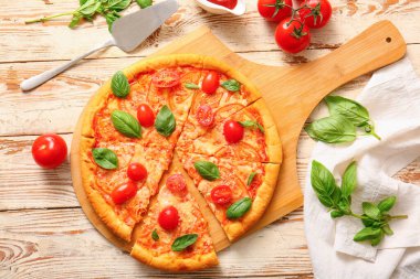 Beyaz ahşap arka planda lezzetli pizza margaritası olan bir pano.