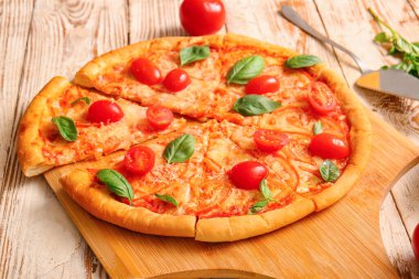 Beyaz ahşap arka planda lezzetli pizza margaritası olan bir pano.