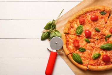 Beyaz ahşap arka planda lezzetli pizza margaritalı fırın kağıdı.