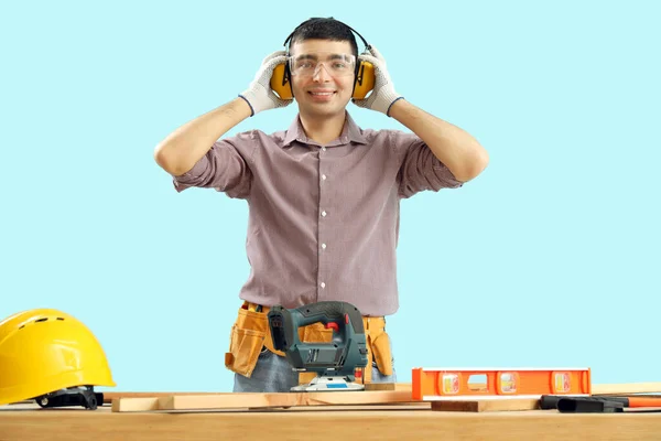 Young Carpenter Hearing Protectors Table Blue Background — Stock Photo, Image