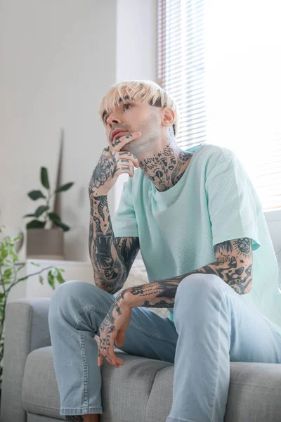 Προσεκτικός Νεαρός Άνδρας Τατουάζ Που Κάθεται Στον Καναπέ Στο Σπίτι — Φωτογραφία Αρχείου