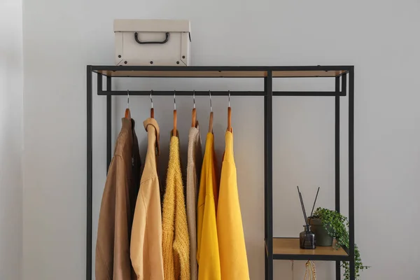 Shelving unit with clothes and box near light wall