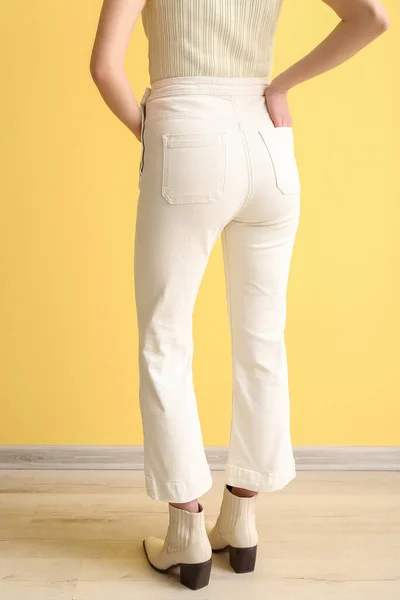 黄色の壁の近くに白いジーンズの若い女性 バックビュー — ストック写真