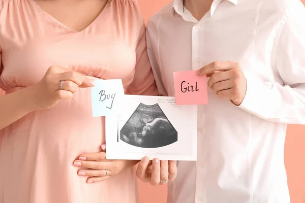 若いです妊娠中のカップル保持Sonogram画像と論文とともに赤ちゃんの性別上のピンクの背景 — ストック写真