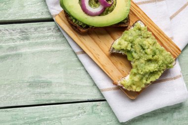 Hafif ahşap arka planda lezzetli avokado tostları.