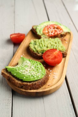 Hafif ahşap arka planda lezzetli avokado tostu.