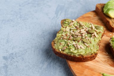 Gri arka planda lezzetli avokado tostu, yakın plan.