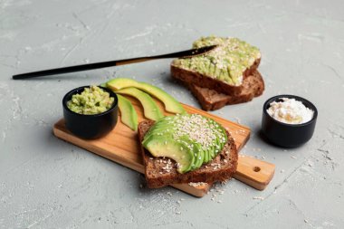 Hafif arka planda tahtadan lezzetli avokado tostu.