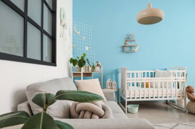 Bebek beşiği, kanepesi ve raf ünitesi olan şık bir yatak odası.