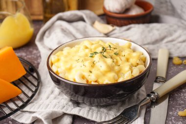 Bir kase lezzetli İtalyan makarnası ve masada Çedar peyniri.