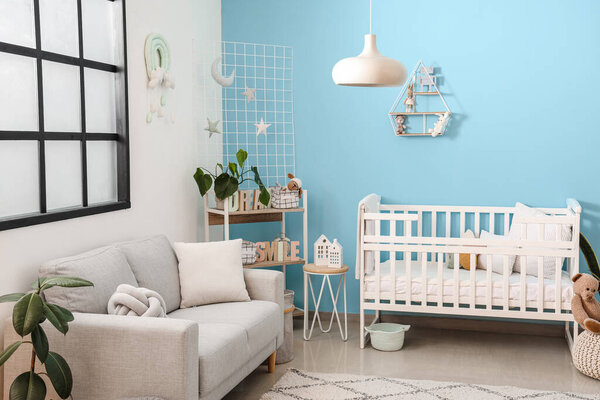 Interior of stylish bedroom with baby crib, sofa and shelving unit