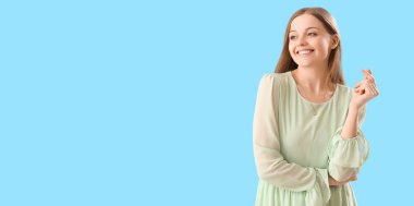 Güzel genç bir kadın, açık mavi arka planda, mesaj için yeri olan bir kalp yapıyor.