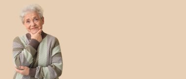 Bej arka planda süveter giyen, mesaj için yeri olan yaşlı bir kadın.