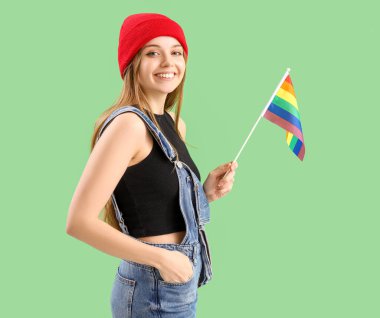 Beautiful young woman with LGBT flag on green background