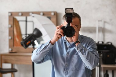 Stüdyoda profesyonel fotoğraf makinesi olan olgun bir fotoğrafçı.