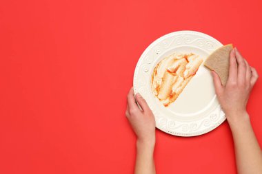 Kırmızı arka planda kirli tabakları yıkayan kadın