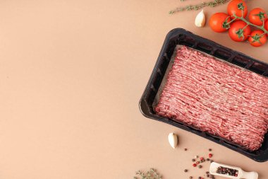 Taze kıyma, domates, sarımsak ve bej arka planda biber içeren plastik paket.