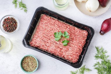 Beyaz grunge arka planında taze kıyma, baharat ve otlardan oluşan plastik paket ile kompozisyon