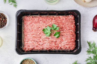 Taze kıymalı plastik paket ve beyaz grunge arka planda maydanoz.